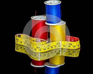 Yellow meauring tape and colorful sewing thread