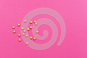 Yellow medicine pills on pink background