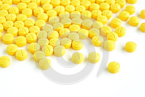 Yellow medicine tablets (or pills) on white background