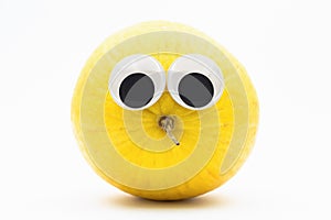 Yellow melon with googly eyes on white background