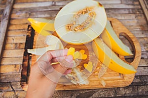 Yellow melon slices with shape heart in female hand