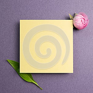 Yellow memo pad with pink flower on purple background