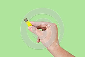 Yellow memory stick on hand with green background