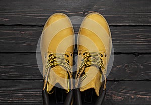 Yellow men`s work boots from natural nubuck leather on dark wooden background top view flat lay with copy space. Trendy casual