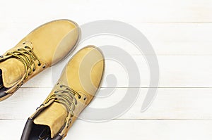 Yellow men`s work boots from natural nubuck leather on wooden white background top view flat lay with copy space. Trendy casual