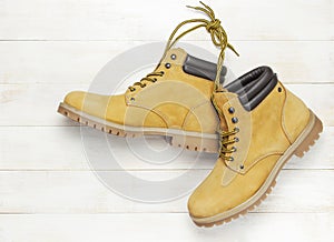 Yellow men`s work boots from natural nubuck leather on wooden white background top view flat lay with copy space. Trendy casual