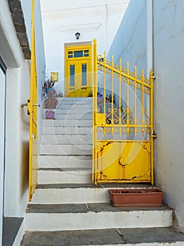 Yellow metal gate same color door pots stairs. Sifnos island Apollonia Cyclades Greece. Vertical