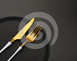 Yellow metal knife and fork on a black background