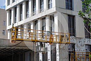 Yellow metal platform to lift workers to produce facade work