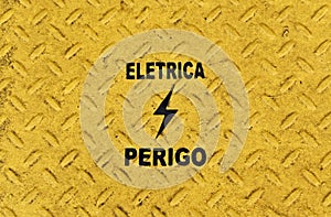 Yellow metallic surface with portuguese words that mean ELETRICITY and DANGER photo