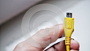 yellow micro USB cables adapter, USB universal plug cable, mobile phone accessory charger on hand white background isolated.