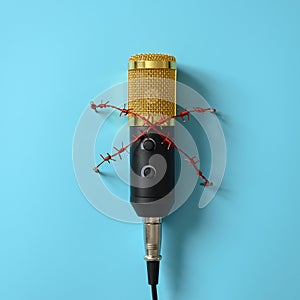 Yellow microphone with red barbed wire. Concept for the topic of censorship or freedom of the press
