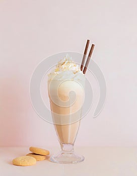 Yellow milkshake with cream and drinking straw on colorful background