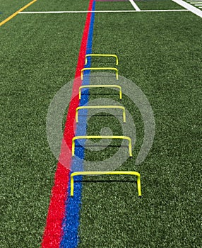 Yellow mini agility hurdles on a green turf field