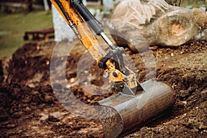 Yellow mini excavator working with earth, moving soil and doing landscaping works