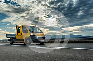 Yellow Mini Truck - Utility transportation van or mini truck driving on a highway