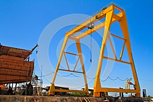 Yellow mobile crane and ship under construction