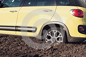Yellow modern SUV car stuck in the mud. Broken vehicle.