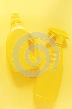 Yellow monochrome flat lay of cleaning tools: spray bottles.