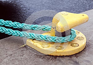 Yellow mooring bollard with green ropes photo