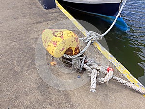 Yellow mooring bollard with ropes