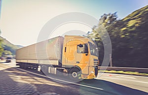 Yellow moving DAF truck coupled with semi-trailer in motion located on the road