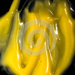Yellow mustard smeared over black background