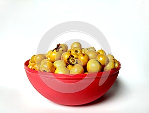 Yellow nances Central American fruit in a red bowl with white background. typical guatemala fruit