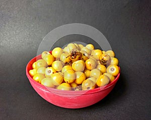 Yellow nances in red bowl with black background