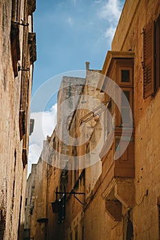 Yellow narrow medieval street with typical maltese balcony in Mdina, ancient capital of Malta, fortified medieval town. Popular