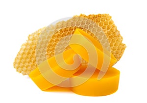 Yellow natural bee wax with a piece of honey cell on a white background.