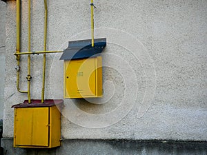 Yellow natural gas pipes and boxes close up on dirty wall