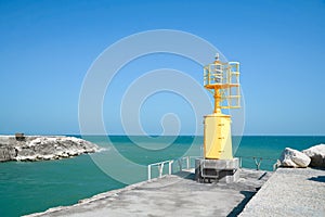 Yellow navigational aid beacon with solar battery on pier