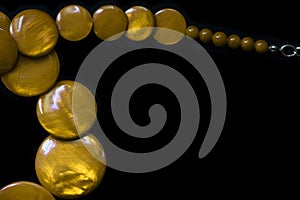 Yellow necklace made of round flat beads on a dark background