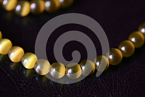 Yellow necklace of stone beads cat`s eye on a dark background