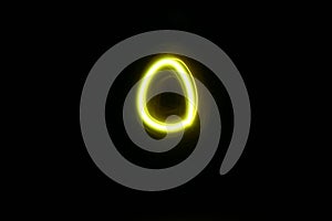 Circle-oval shaped yellow neon light suspended in black space photo