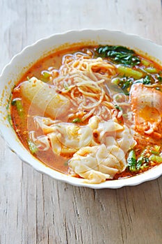 Yellow noodle with pork dumpling in spicy soup on bowl