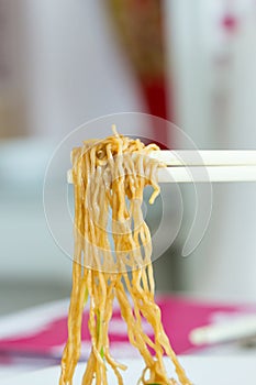 Yellow noodles with chopstick holding
