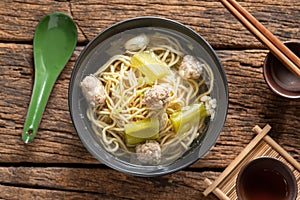Yellow noodles in clear broth with bitter melon and ground pork