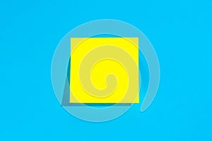 Yellow note with empty place for text on a blue background, flat lay.