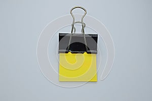 Yellow note paper with black binder clip. Binder clip and stack of yellow note paper