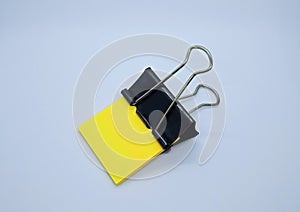 Yellow note paper with black binder clip. Binder clip and stack of yellow note paper