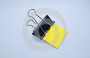 Yellow note paper with black binder clip. Binder clip and stack of yellow note paper