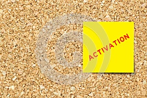 Yellow note paper with word activation on cork board with copy space