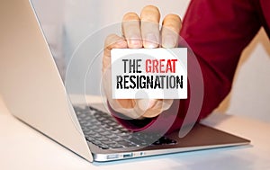 Yellow note stick on notebook with red text THE GREAT RESIGNATION
