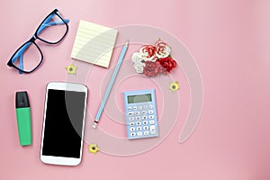 Yellow notebook mobile phone calculator and hilight marker blue glasses on pink background pastel style with copyspace flatlay