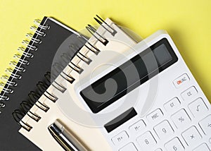 Yellow office desk ot table with calculator, pen and notebooks