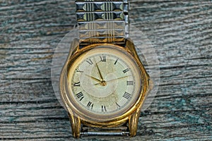 yellow old shabby watch with a metal strap on a gray table