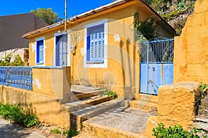 Yellow old typical house with blue windows and shutters in Assos village, Kefalonia island, Greece