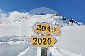 yellow panel 2019 and 2020 in front of snowy mountain landscape under blue sky